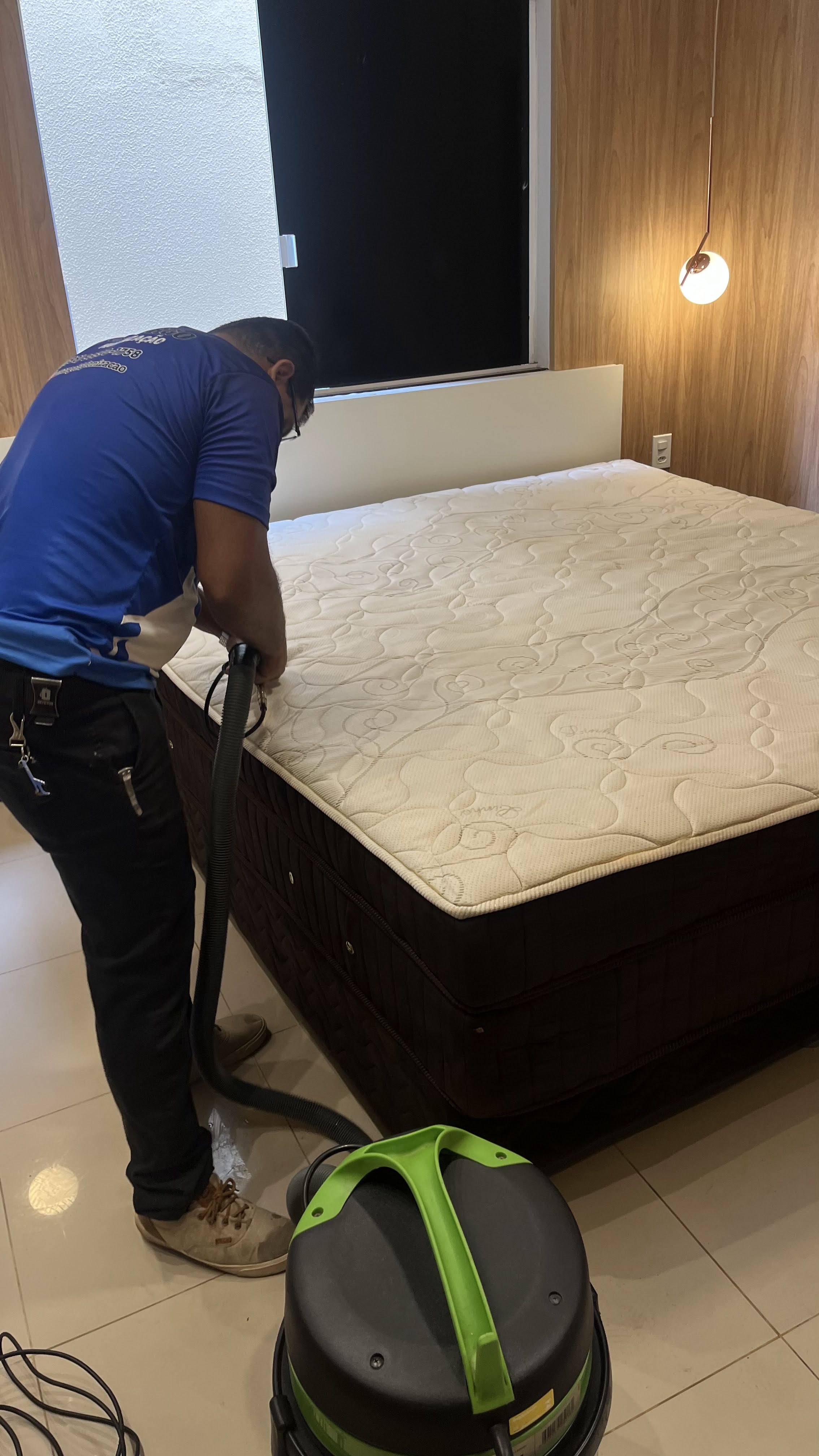 Profissional higienizando colchão de casal com equipamento profissional
